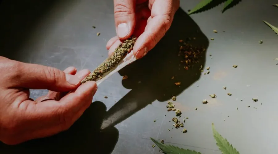 Hands rolling a joint on a flat surface