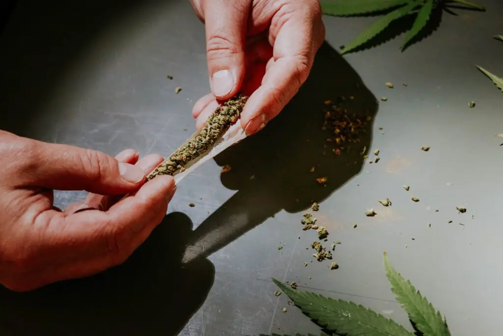 Hands rolling a joint on a flat surface